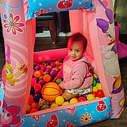 Sophia joined the competition — help win amazing prizes! child, toddler, ball_pit, inflatable_playhouse, plastic_balls, basketball, pink, toy, play, indoor, smile, sweater, floor, curtain, chair, wood_floor, cartoon_character, colorful, happy, portrait