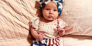 Emerson Rae is registered to the contest to win money with this photo: baby, bed, blue, bow, child, clothing, cute, expression, fabric, headband, indoors, infant, pillow, portrait, red, sitting, soft, stars, stripes, white
