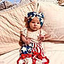 baby, bed, blue, bow, child, clothing, cute, expression, fabric, headband, indoors, infant, pillow, portrait, red, sitting, soft, stars, stripes, white