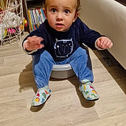 Ethan participe au concours pour gagner de l'argent avec cette photo : basin, blue_pants, books, bookshelf, child, colorful_socks, curly_hair, expression, face, floor, furniture, hand, home, indoor, room, sitting, sweater, toddler, toy, wood_floor