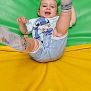 Ethan a rejoint le concours — aidez-le/la à gagner de superbes lots ! active, baby, cartoon_print, child, cute, denim_shorts, green_background, happy, indoor, joyful, legs, padded_surface, person, playful, smiling, socks, toddler, tshirt, yellow_background, young_child