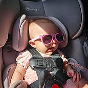 Willow is registered to the contest to win money with this photo: baby, car_seat, child, clothing, cute, face, hand, headrest, infant, interior, pink_dress, pink_sunglasses, relaxing, safety, seat, seatbelt, straps, sunlight, toddler, vehicle