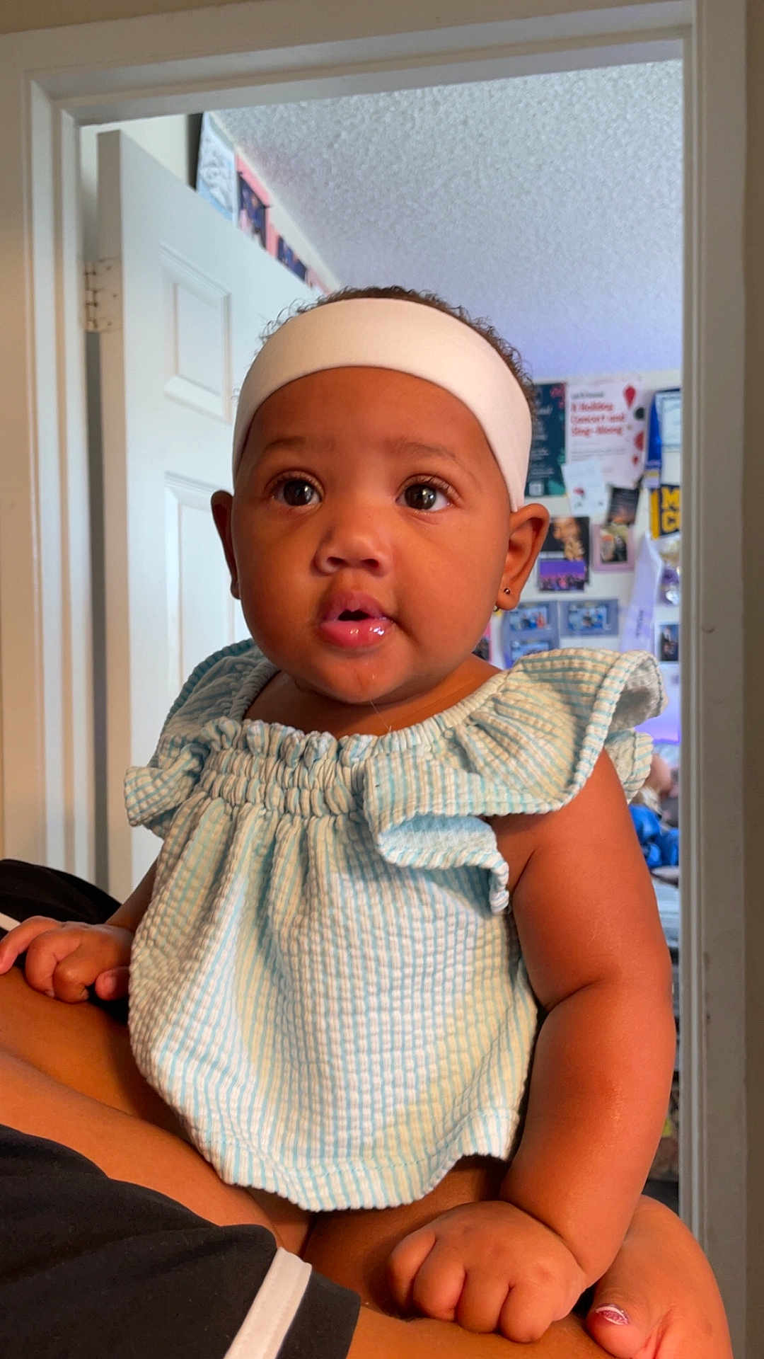 Je Nai is registered to the contest to win money with this photo: baby, child, headband, drool, blue_striped_top, curious, indoor, person, holding, arm, hand, face, eyes, earring, door, wall, photography, portrait, skin, expression