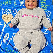 Nezuko joined the competition — help win amazing prizes! baby, infant, three_months, child, smiling, tongue_out, portrait, lying_down, blanket, blue_blanket, gray_outfit, sweatshirt, pants, champion_logo, heart_sign, milestone_photo, indoor, happy, face, photography