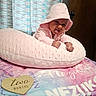 Nezuko is registered to the contest to win money with this photo: baby, infant, child, portrait, smiling, tongue_out, pink_clothing, hood, pajamas, pillow, milestone, two_months, heart_sign, bed, blanket, curtain, indoor, happy, sitting, photography