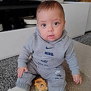 Omar a rejoint le concours — aidez-le/la à gagner de superbes lots ! baby, child, sitting, grey_clothing, nike, carpet, toy, teether, indoor, furniture, television, face, cute, young_child, floor, socks, hoodie, pants, person, home