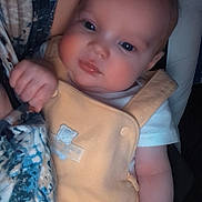 Madison is registered to the contest to win money with this photo: baby, infant, child, yellow_overall, blue_eyes, soft_lighting, close_up, person, cute, hand, skin, clothing, portrait, indoor, cuddle, adult_arm, comfort, warm, expression, human