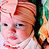 baby, infant, headband, bow, face, closeup, blanket, bib, clothing, cute, expression, portrait, skin, soft_lighting, child, newborn, lying_down, indoors, apparel, headwear