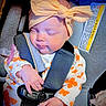 baby, bow, buckle, car_seat, car_seat_strap, closed_eyes, cozy, fabric, floral_outfit, hand, headband, infant, newborn, onesie, pacifier, portrait, safety_warning_label, seat_padding, sleeping, tiny_fingers