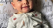 Charlie joined the competition — help win amazing prizes! baby, infant, smile, face, eyes, onesie, clothing, hand, cushion, text, pattern, cute, indoors, portrait, child, happy, expression, soft, cozy, background