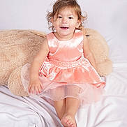 Mya participe au concours pour gagner de l'argent avec cette photo : toddler, child, dress, peach, smile, plush_toy, teddy_bear, blanket, soft_texture, indoors, cute, happy, sitting, barefoot, portrait, curly_hair, young_child, studio_photo, fabric, comfortable