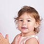 toddler, child, clapping, curly_hair, smiling, portrait, dress, peach_color, face, hands, cute, happy, studio, light_background, young_child, skin, expression, innocent, closeup, person