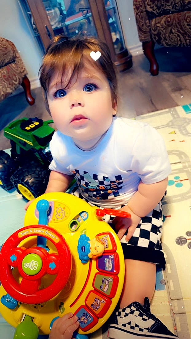 Daxton is registered to the contest to win money with this photo: automotive_tire, automotive_wheel_system, baby_toddler_clothing, blue, child, circle, electric_blue, eye, facial_expression, fun, happy, leisure, person, plastic, play, recreation, sitting, sleeve, t_shirt, toddler