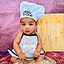 apron, baby, chef_hat, child, cooking, cute, expression, floor, flour, food_preparation, glass_bowl, hands, indoors, kitchen, playful, portrait, purple_background, sitting, small_child, wooden_floor