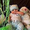 Kaine is registered to the contest to win money with this photo: baby, child, bunny_hat, stuffed_animal, plush_toy, blue_pants, white_shirt, green_shredded_paper, black_background, baby_sitting, hand_in_mouth, cute, indoor, soft_toy, hat, infant, portrait, playful, toy, colorful