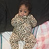 baby, infant, child, portrait, sitting, bed, bedding, pillow, blanket, leopard_print, outfit, clothing, curly_hair, wide_eyed, face, indoors, home, cozy, photograph, smiling