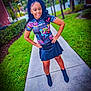 child, girl, sidewalk, outdoor, grass, trees, pigtails, smile, black_skirt, boots, colorful_shirt, hands_on_hips, residential_area, greenery, person, young_girl, fashion, casual, portrait, daylight