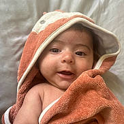 Santiago joined the competition — help win amazing prizes! baby, child, towel, hood, smile, face, skin, arm, blanket, cute, infant, wrapped, soft, texture, happy, portrait, lying_down, indoors, closeup, expression
