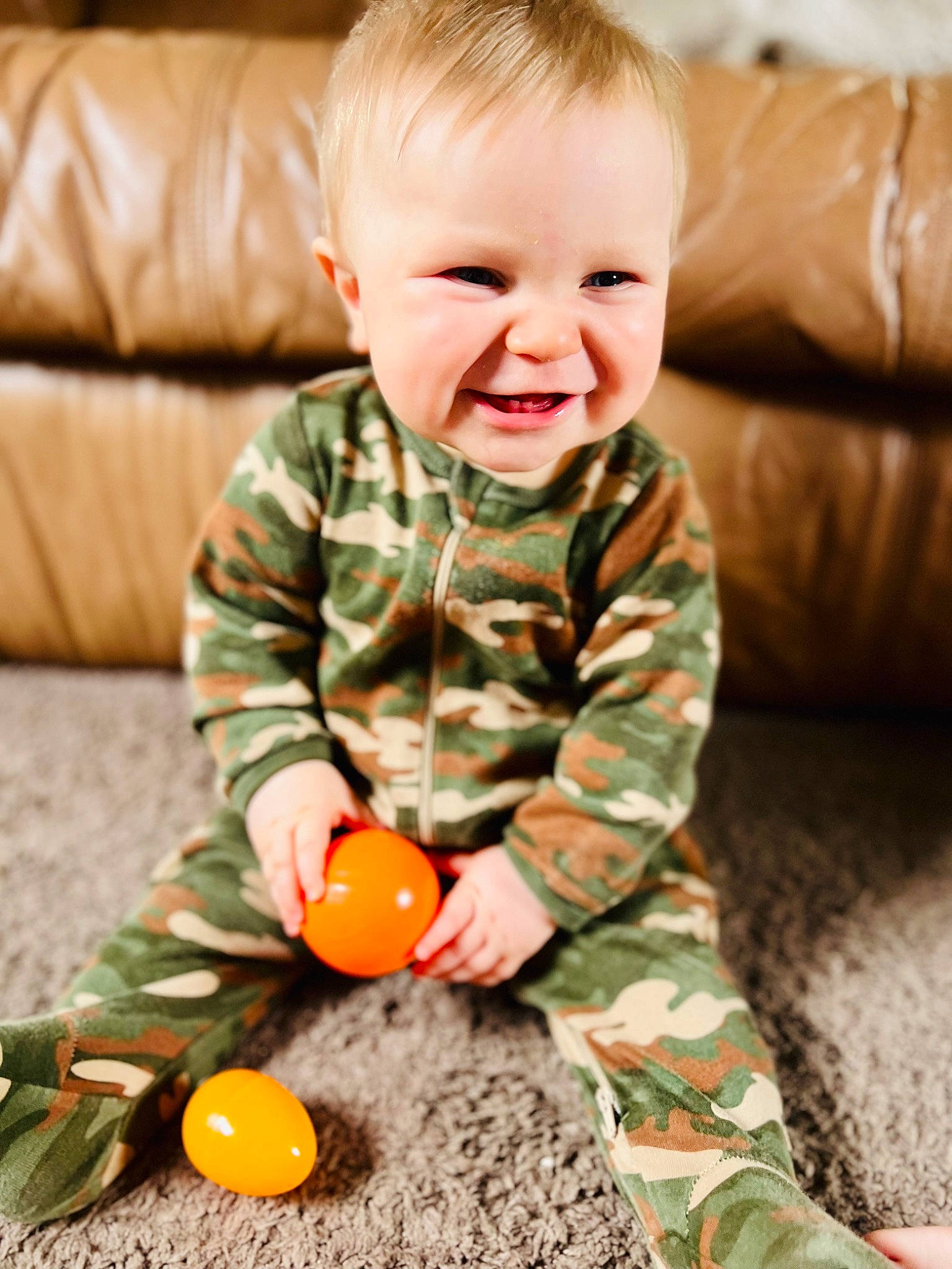 Braxton is registered to the contest to win money with this photo: baby_toddler_clothing, cheek, comfort, face, facial_expression, floor, flooring, green, hair, happy, head, nose, orange, person, photograph, skin, sleeve, smile, toddler, wood