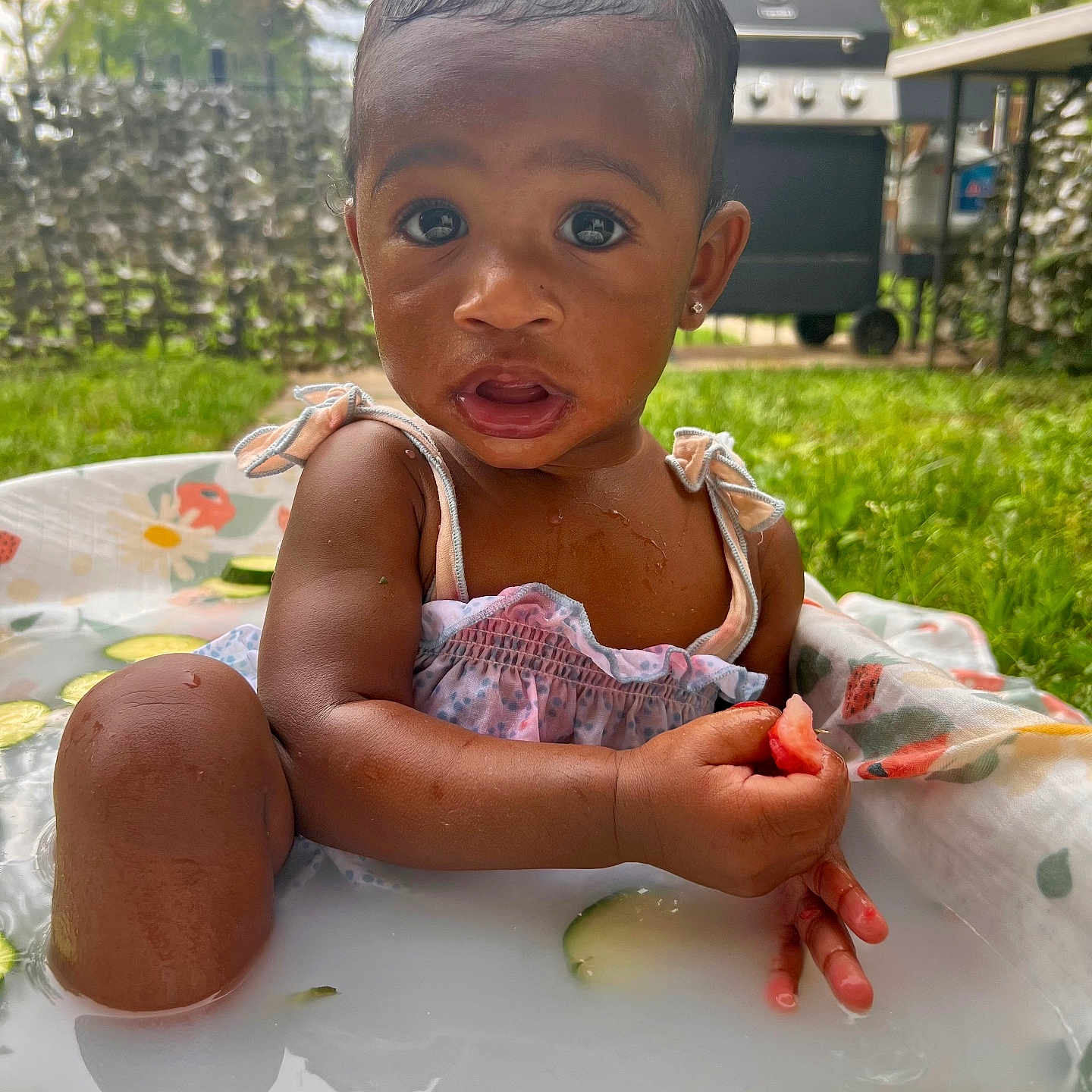 Rui is registered to the contest to win money with this photo: backyard, child, cucumber_slices, cute, dress, earrings, expression, food, fun, garden, grass, milk_bath, outdoor, play, sitting, summer, toddler, water, watermelon, wet_hair