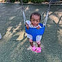 child, toddler, swing, playground, smiling, happy, outdoor, tree, greenery, fence, footwear, pink_sandals, clothing, white_dress, metal_chains, rubber_surface, sunlight, shadow, person, cute