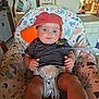 baby, infant, cap, orange_cap, striped_shirt, baby_seat, patterned_seat, indoor, kitchen, furniture, plastic_bag, cabinet, door, person, child, face, hands, legs, curious, blue_eyes