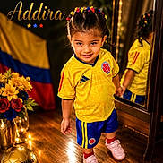 Aadhira Rastogi is registered to the contest to win money with this photo: blue_shorts, braided_hair, child, colombian_flag, colorful_hair_accessories, flowers, girl, golden_soccer_ball, happy, indoor, mirror, pink_shoes, portrait, reflection, smiling, soccer_uniform, sports, text_overlay, wooden_floor, yellow_jersey