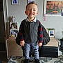 Naseylio participe au concours pour gagner de l'argent avec cette photo : child, clothing, decor, face, furniture, happy, home, indoor, interior, pants, person, picture_frame, plaid_shirt, plant, shoes, smiling, standing, table, toddler, vest