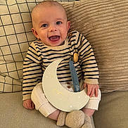 Léon participe au concours pour gagner de l'argent avec cette photo : baby, infant, smiling, couch, pillow, striped_sweater, booties, crescent_moon, sign, 3_months, indoor, cozy, happy, child, portrait, seated, plush, comfortable, cute, young
