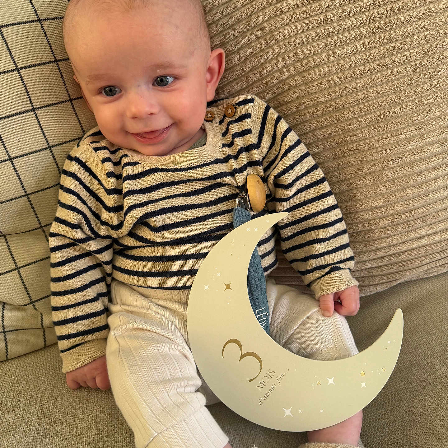 Léon participe au concours pour gagner de l'argent avec cette photo : baby, child, infant, couch, striped_sweater, boots, crescent_moon, sign, cushions, smiling, sitting, indoors, cute, portrait, cozy, soft_toys, home, comfortable, young, happy
