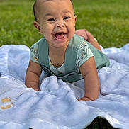 Tiana joined the competition — help win amazing prizes! baby, smiling, outdoor, grass, blanket, child, happy, cute, infant, toddler, clothing, person, face, portrait, greenery, nature, lying_down, young_child, playful, sunlight