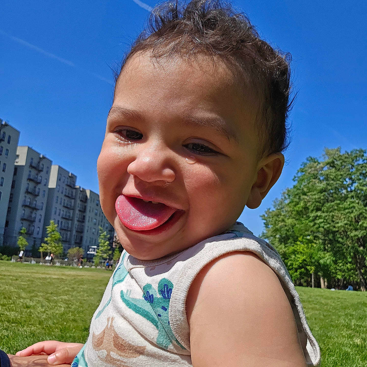 Oliver joined the competition — help win amazing prizes! toddler, child, grass, outdoor, sunny, blue_sky, building, tree, smiling, tongue_out, happy, person, casual_clothing, daylight, playful, nature, park, closeup, skin, hair