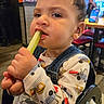 Oliver joined the competition — help win amazing prizes! toddler, child, celery, food, eating, overalls, shirt, high_chair, indoor, restaurant, table, chair, person, face, hands, expression, food_item, furniture, casual, background