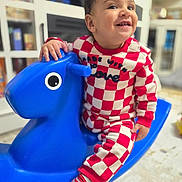 Oliver joined the competition — help win amazing prizes! toddler, child, smile, indoor, rocking_horse, toy, red_and_white_checkered_outfit, striped_socks, happy, playful, furniture, cabinet, floor, face, person, cute, young_child, playtime, colorful, home