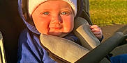Koa joined the competition — help win amazing prizes! baby, child, stroller, hoodie, knit_hat, blue_clothing, outdoor, sunlight, grass, smile, face, hand, safety_harness, seat, park, daytime, cute, portrait, infant, warm_clothing
