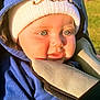 baby, child, hoodie, hat, blue_eyes, stroller, outdoor, sunlight, close_up, face, clothing, winter_wear, cute, infant, warm_clothes, portrait, baby_hand, sitting, daylight, nature