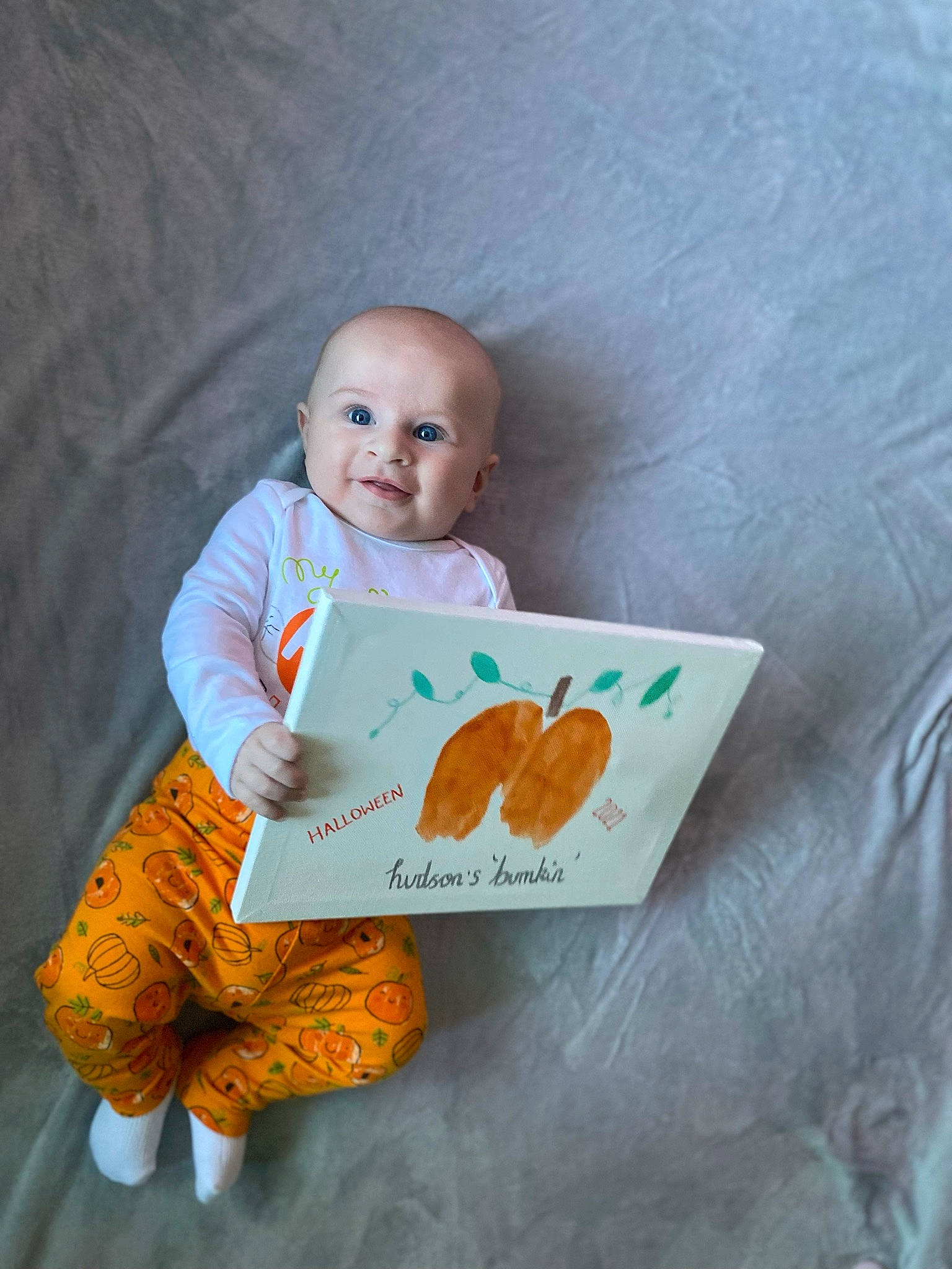 Hudson is registered to the contest to win money with this photo: azure, baby, baby_products, baby_toddler_clothing, calabaza, child, doll, happy, linens, orange, person, product, pumpkin, sleeve, smile, stuffed_toy, t_shirt, textile, toddler, vegetable