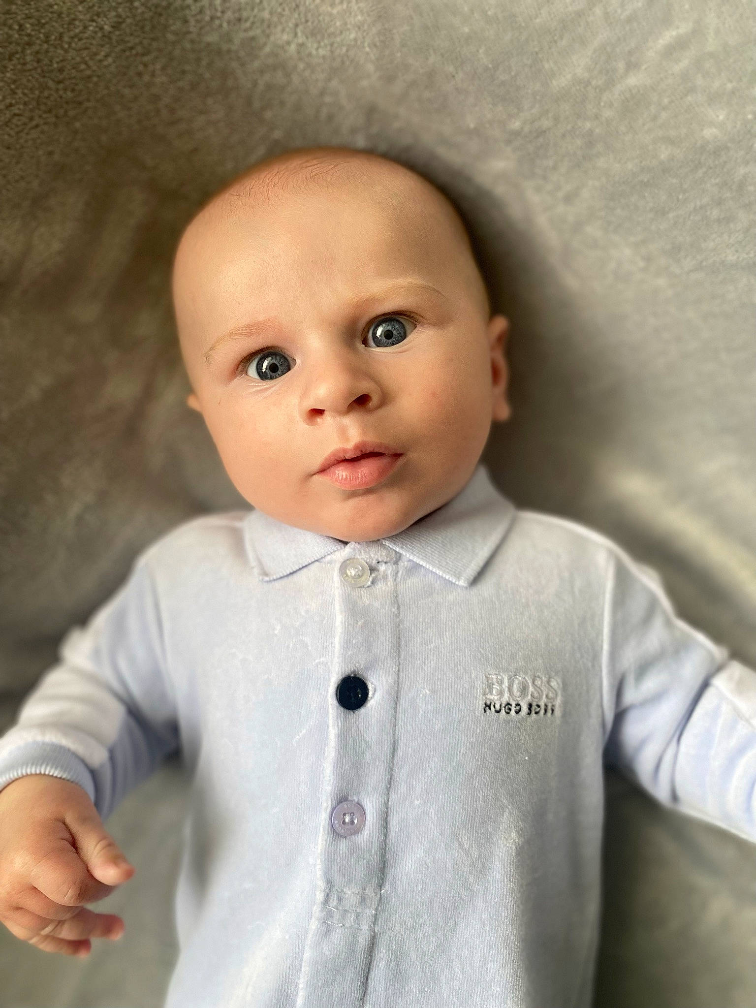 Hudson is registered to the contest to win money with this photo: baby_toddler_clothing, cheek, chin, dress_shirt, eye, eyebrow, eyelash, forehead, gesture, joint, lip, mouth, neck, nose, outerwear, person, skin, sleeve, textile, toy