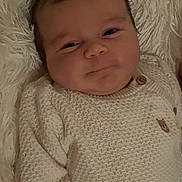 Jason is registered to the contest to win money with this photo: baby, infant, sweater, knitwear, smile, face, hair, cute, lying_down, blanket, soft_texture, child, portrait, cozy, indoors, young, happy, skin, person, expression