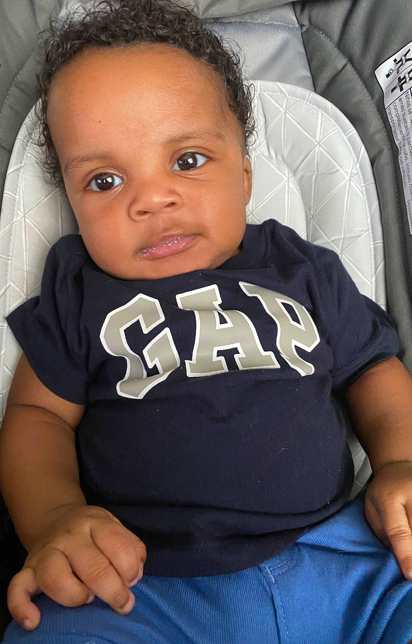 Andrew is registered to the contest to win money with this photo: arm, baby_toddler_clothing, black, black_hair, car_seat, chest, child, comfort, elbow, eyebrow, flash_photography, forehead, hairstyle, happy, human_leg, person, sitting, sleeve, smile, t_shirt