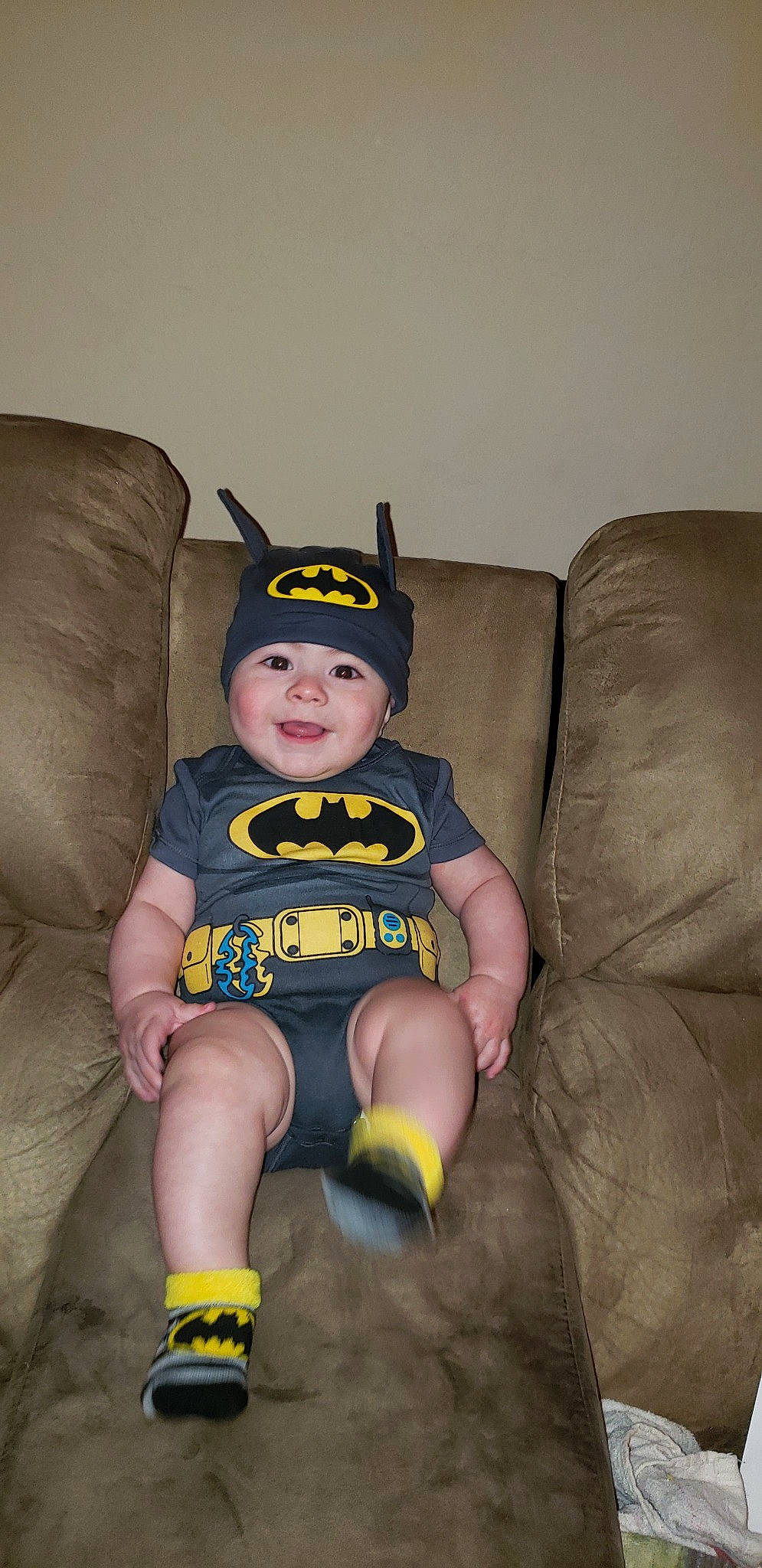 Donte' is registered to the contest to win money with this photo: arm, batman, chair, child, costume, fictional_character, fun, head, headwear, joy, justice_league, leg, person, sitting, skin, smile, superhero, toddler, yellow