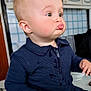 Maxson is registered to the contest to win money with this photo: toddler, child, indoor, face, expression, pout, plush_toy, clothing, sweater, hand, table, kitchen, cabinet, tile_wall, person, cute, baby, funny_face, seated, light_skin