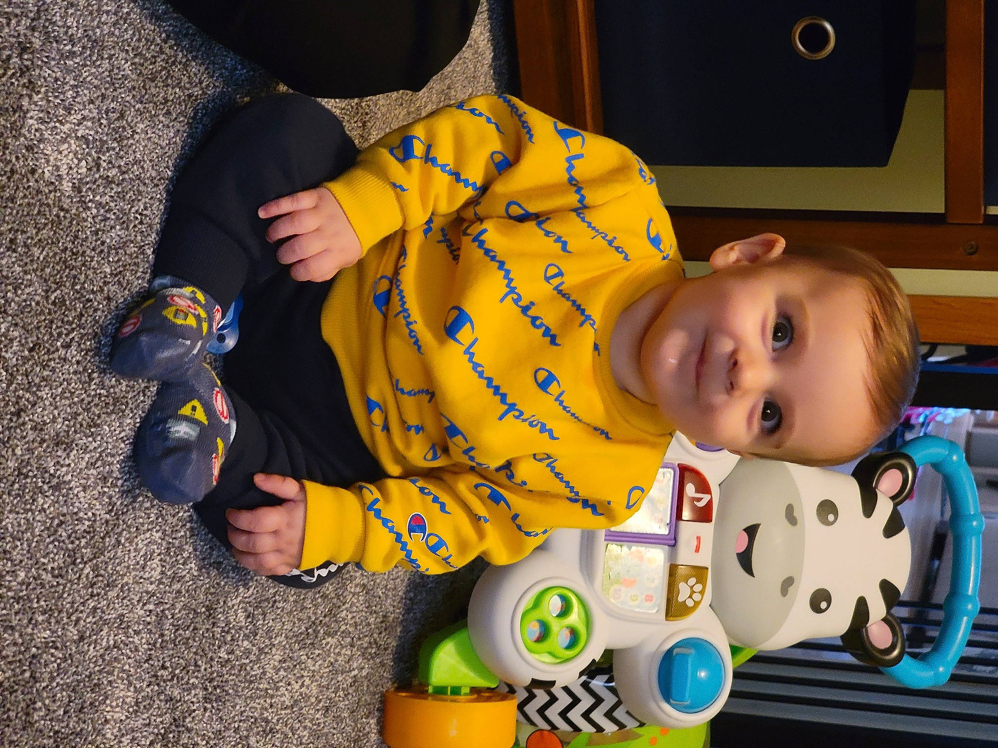 Alden joined the competition — help win amazing prizes! baby, baby_products, baby_toddler_clothing, baby_toys, child, comfort, flooring, fun, happy, musical_instrument, person, play, room, sitting, smile, television, toddler, toy, yellow