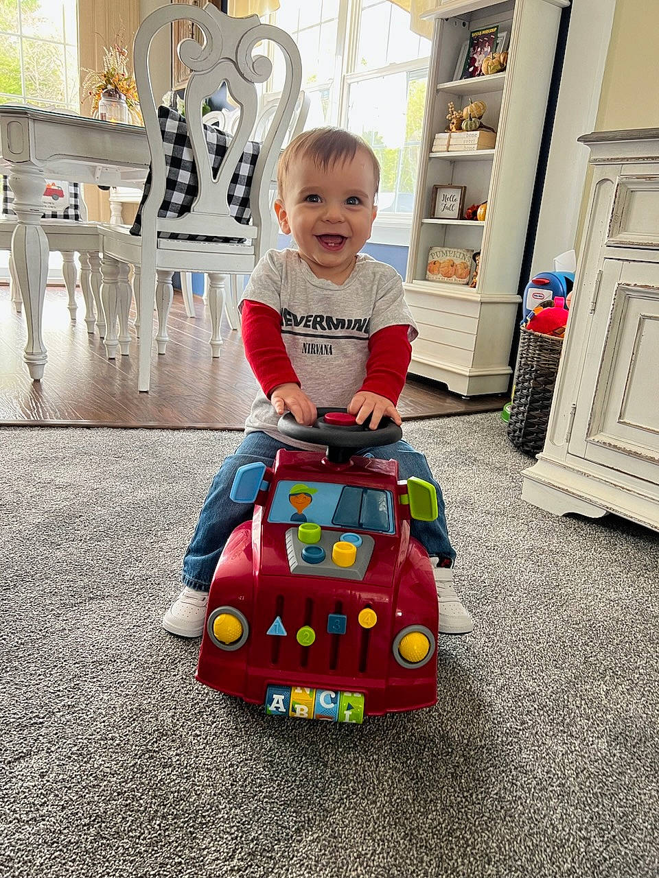 Alden is registered to the contest to win money with this photo: baby, baby_products, baby_toddler_clothing, baby_toys, child, door, event, floor, flooring, fun, joy, motor_vehicle, person, play, recreation, riding_toy, room, sitting, smile, toddler