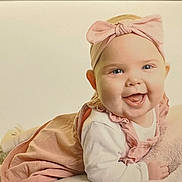 Madelyn Marsden joined the competition — help win amazing prizes! baby, infant, smiling, headband, pink, clothing, cute, happy, lying_down, soft_surface, child, portrait, indoors, toddler, face, skin, eyes, mouth, hand, cozy