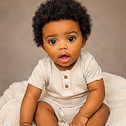 Amilliyon joined the competition — help win amazing prizes! baby, infant, curly_hair, cute, soft_blanket, sitting, expressive_eyes, skin, onesie, portrait, child, adorable, curious, hands, feet, indoor, studio, neutral_background, young, person