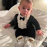 Anton a rejoint le concours — aidez-le/la à gagner de superbes lots ! baby, bear_design, bedroom, black_and_white, blanket, bow_tie, child, clothing, cute, footwear, indoors, infant, person, portrait, sitting, small_shoes, socks, soft_lighting, tuxedo, white_bed