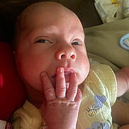 Timothy is registered to the contest to win money with this photo: baby, infant, face, hand, fingers, yellow_clothing, close_up, curious_expression, skin, person, newborn, resting, indoor, soft_lighting, cute, young_child, portrait, baby_garment, human, small_hand