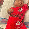 baby, sleeping, red_clothing, headband, bow, blanket, infant, patches, cute, resting, child, person, soft_lighting, indoors, comfortable, peaceful, portrait, newborn, casual, relaxed