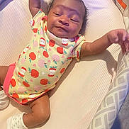 Icelynn joined the competition — help win amazing prizes! baby, infant, child, onesie, apple_pattern, cushion, sleepy, cute, lying_down, soft_surface, sock, arm_stretch, content, indoor, fabric, pattern, head, skin, person, newborn
